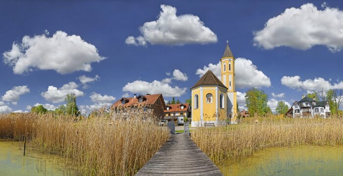 Reed-covered shore at the Lake Ammer and the Sant Alban church with white blue sky, Die&szlig;en, Lake Ammer, Bavaria, Germany