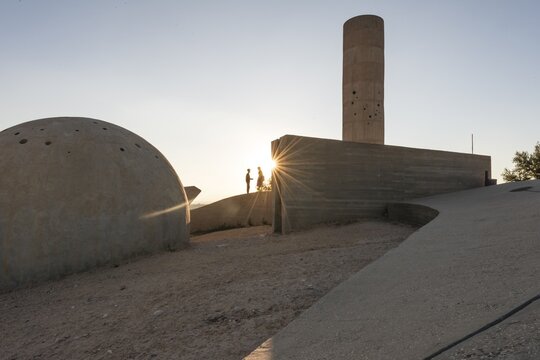 Two people standing at the concrete monument, Monument of the Negev Brigade, Sun in the evening, Be'er Sheva, Israel