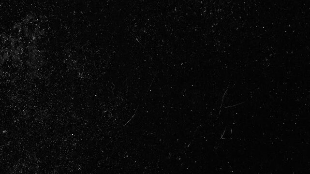 Black background with scattered white dust and scratches