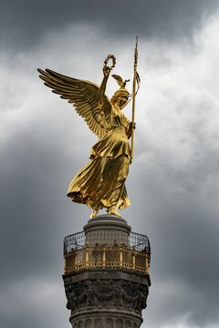 Golden bronze sculpture of Victoria on the Victory Column, inaugurated 1873, dark sky, Berlin, Germany