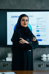 Arab businesswoman wearing abaya leading corporate presentation showing financial results