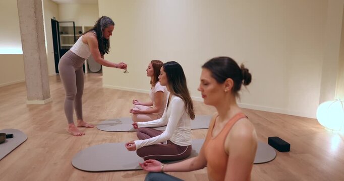 Yoga instructor offering a glass of wine to a student during a mindful meditation class, a unique spiritual practice combining relaxation, sensory awareness, and wellness in a modern studio