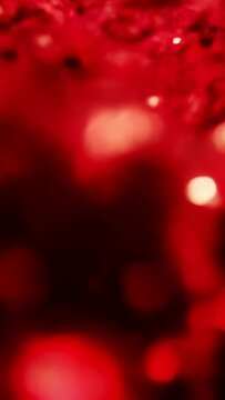 Vertical video: Rising bubble cluster drifting in tube, buoyancy lifting spheres, glossy red liquid