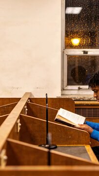 Vertical video: Starting, student in blue top reading paperback at carrels for study, copy space