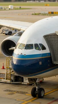 Camera pulling back, revealing nose and cockpit, ramp crew operating loader for aviation turnaround