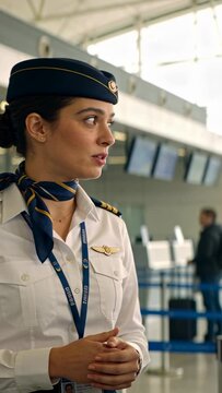 Vertical video: Female airline staff answering guest question showing checkin at screens gesturing
