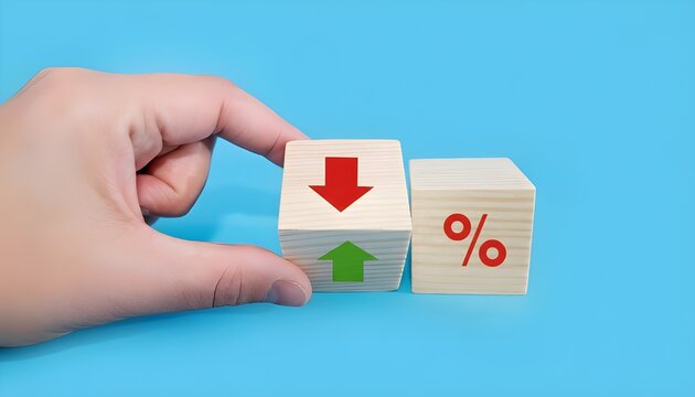 A hand pushing a wooden block with up and down arrows next to a percentage symbol, representing changing interest rates or economic trends.
