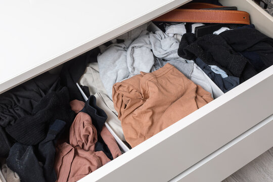 Open dresser drawer with mixed casual clothes shows home wardrobe clutter, storage overflow and everyday organization problem.