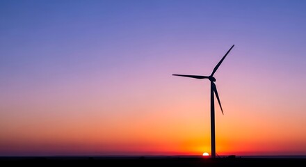 Obraz premium Wind turbine standing tall against vibrant sunset sky with orange hues and silhouetted blades in a serene landscape scene at dusk outside