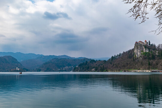 Lake Bled landscape with church and castle under dramatic cloudy sky in Slovenia with calm water surface