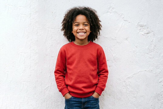 Photo of an African-American child in a red sweater against a white street wall