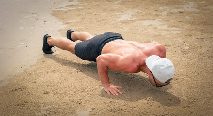 Young healthy man workout exercise on the beach at daytime