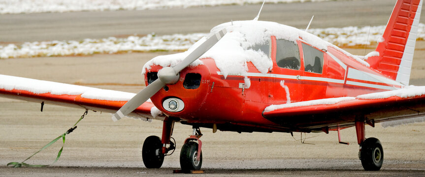 Small Red Airplane Single Engine Private Plane on Runway Covered in Snow in the Winter Wintery Snowy