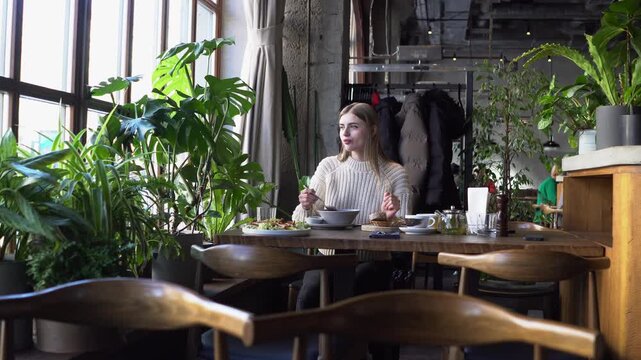 young beautiful woman eats borscht with spoon in cafe, girl eats soup with lard and bread in restaurant