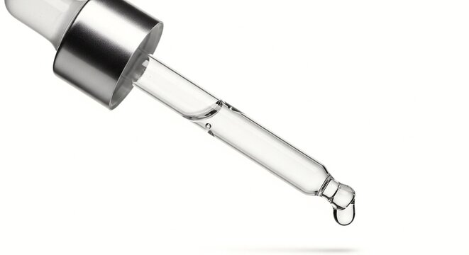 A close-up view of a glass dropper with a single drop of liquid falling from the tip