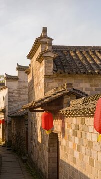 Vertical video: Swaying red lantern with yellow tassel over stone alley, breeze nudging, copy space