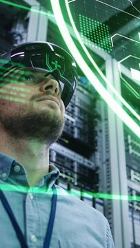 Vertical video: Scanning tech in shirt lanyard viewing headset-HUD checking stats at server racks