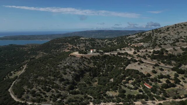 A picturesque view of the Aegean Sea and islands. Green hills dotted with trees and buildings.
