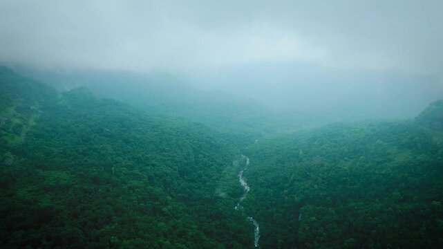 Scenic view of the lush green Western Ghats covered by clouds. 4K Aerial shot of Sahyadri hills and river flowing in valley at Lonavala, Maharashtra, India. Monsoon season trekking and adventure activ