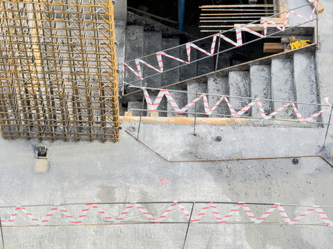 View of a construction site with concrete stairs and rebar, marked by red and white tape, suggesting ongoing work, Avcilar, Istanbul, Turkey.