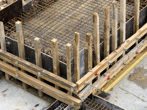 View of raw wooden planks and metal rebar form a stark geometric pattern against the gray concrete, a study in textures and industrial preparation, Istanbul, Istanbul, Turkey.