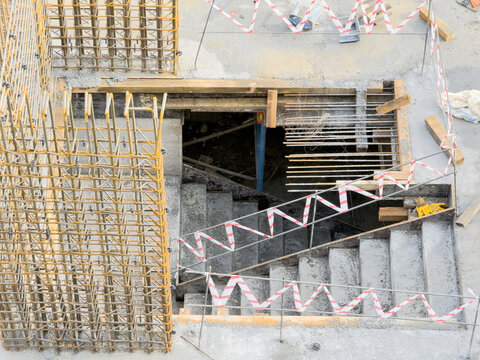 View of the stark concrete steps descend into the shadowed depths of a construction site, marked by caution tape against a backdrop of rebar, Istanbul, Istanbul, Turkey.