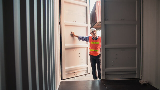 Logistics worker shipping container warehouse safety vest hard hat supply chain cargo transportation freight industry logistics worker standing inside shipping container opening metal door