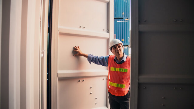 Logistics worker shipping container warehouse safety vest hard hat supply chain cargo transportation freight industry logistics worker standing inside shipping container opening metal door