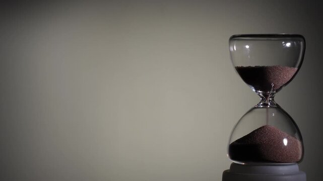 Hourglass flowing on white background. Right align comp with copy space on top and left, time management concept, minimalist product shot, hourglass in motion, clean style, last grains of sand