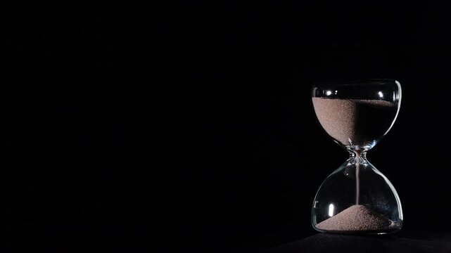 Hourglass flowing on black background. Right align comp with copy space on top and left, time management concept, minimalist product shot, hourglass in motion, clean style, steady flow