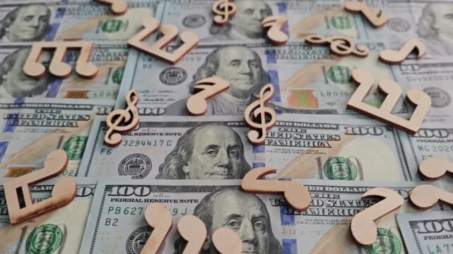 Money and music notes arranged on hundred dollar bills create a unique background for a creative project