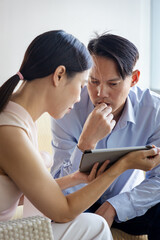 Fototapeta premium Thoughtful Asian businessman looking at sales woman presentation with serious thinking mood, concept of receiving bad news, concept of scam, negative notification, slow internet connection