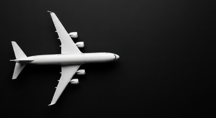 Obraz premium White Toy Airplane Model on Dark Background, Top View with Copy Space for Travel and Aviation Concepts
