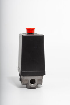 Top-down close-up of an air compressor pressure switch, showing the black plastic housing with technical specifications, a red round on-off power button, and a pressure regulator knob.