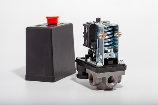 Top-down close-up of an air compressor pressure switch, showing the black plastic housing with technical specifications, a red round on-off power button, and a pressure regulator knob.