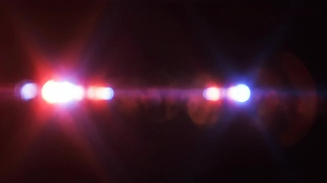 Emergency police lights flashing in red and blue colors. Abstract cinematic anamorphic lens flares and glowing sirens on black background for crime, safety and law video projects.
