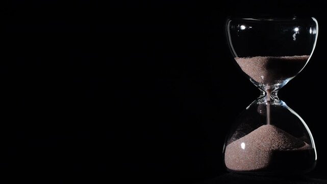 Hourglass flowing on black background. Right align composition with copy space on left, time management concept, minimalist product shot, hourglass in motion, clean style, last grains of sand
