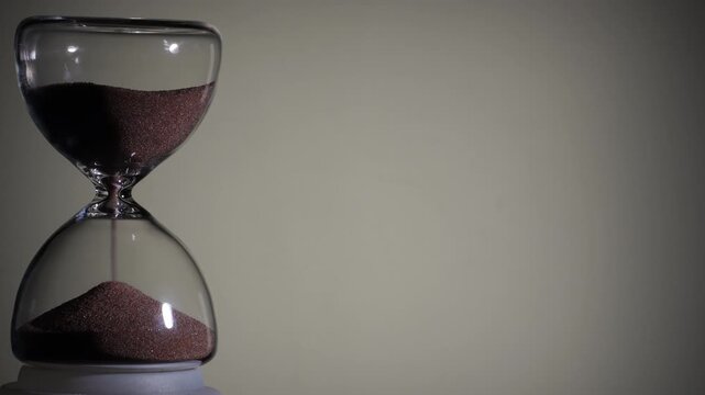 Hourglass flowing on white background. Left align composition with copy space on right, time management concept, minimalist product shot, hourglass in motion, clean style, approaching end
