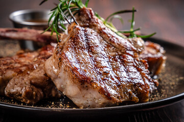 Grilled lamb chops with rosemary on black plate © zukamilov