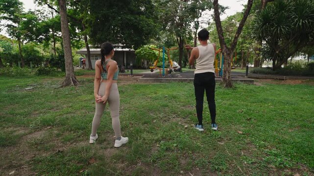 A Latin man and an Asian girl with their backs to camera doing basic gymnasis to stay in shape