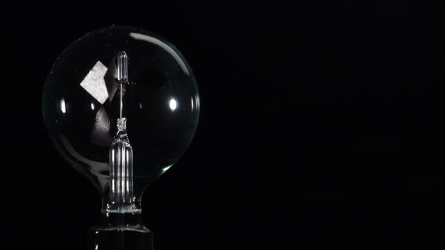 Macro of rotating Crookes radiometer light mill on black background. Left aligned minimalist composition with copy space, physics experiment, solar vane, cinematic lighting