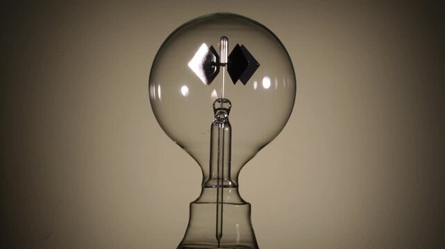 Center align, rotating Crookes radiometer light mill on bright white background. Black start, High-key lighting, minimalist science experiment, solar vane, physics education, left-right copy space