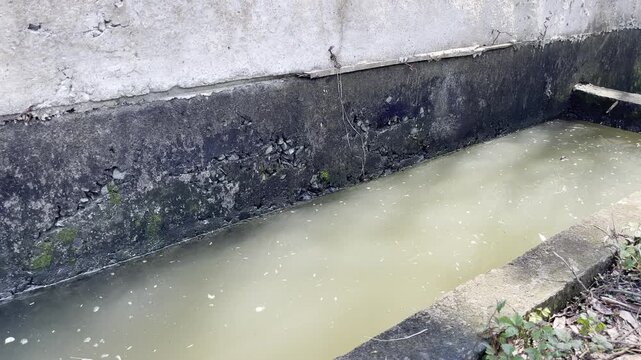 Murky Water Flowing in Concrete Drainage Ditch