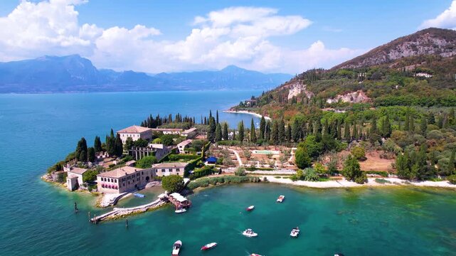 Aerial pull-back view of Punta San Vigilio and Baia delle Sirene at Lake Garda, Italy. Scenic drone shot of historic villa, cypress trees and turquoise bay in northern Italy travel destination, 4k.