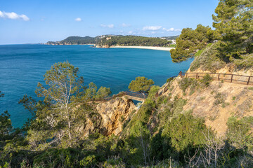 Naklejka premium Scenic coastal path winding along a rugged cliffside offering breathtaking panoramic views of fenals beach and the deep blue mediterranean sea under a clear sky