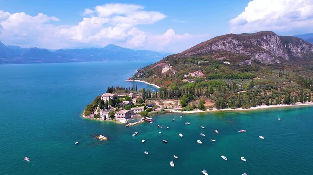 Italy Lake Garda aerial drone fly-in descending to Punta San Vigilio. Romantic peninsula with moving boats and Baia delle Sirene. Luxury travel destination Garda 4k scenic landscape Veneto region