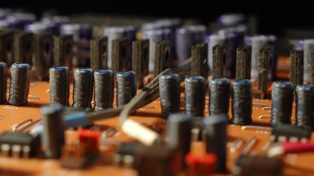 Macro view of high power transistors and capacitors in a precise 3-row array on broadcast PCB. Macro close up of electronic components standing like a military parade.
