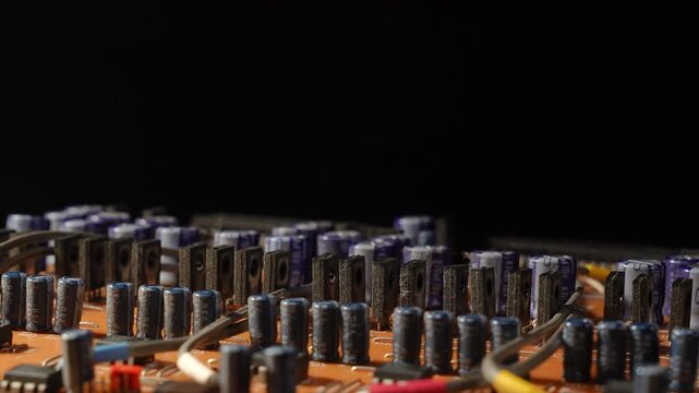 Side profile of high power TO-220 transistors and blue capacitors on broadcast PCB. Macro shot with top copy space, electronic components like a city skyline