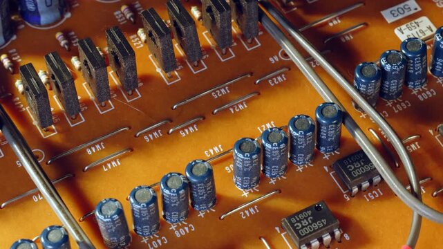 Top view of high power transistors and capacitors in a precise 3-row array on broadcast PCB. Macro close up of electronic components standing like a military parade