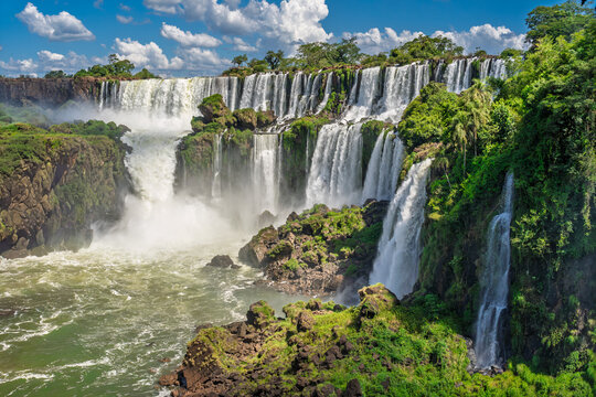 Iguazu Falls Argentina majestic waterfalls stretching across rainforest cliffs with swirling river and misty atmosphere
